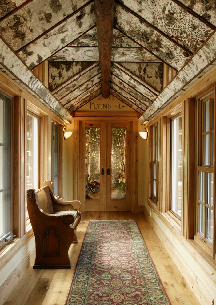 Diseño de hall rústico con suelo de madera clara, puerta doble y puerta de vidrio