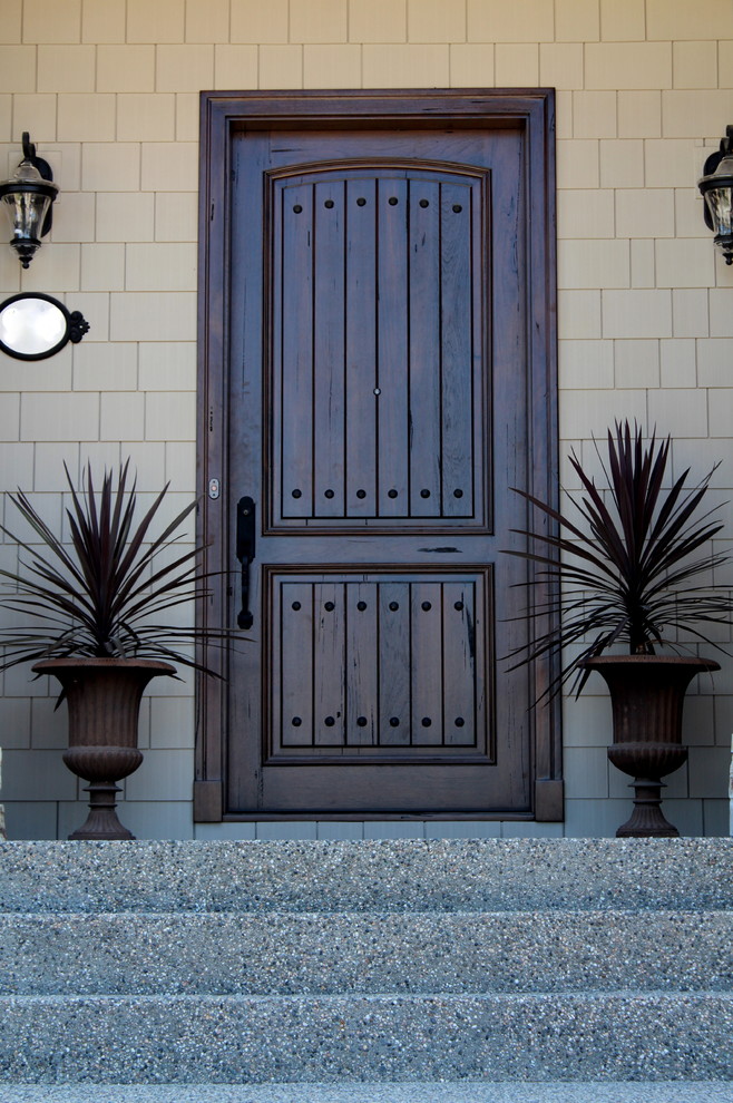 Modelo de puerta principal rústica de tamaño medio con puerta simple, puerta de madera oscura y paredes beige