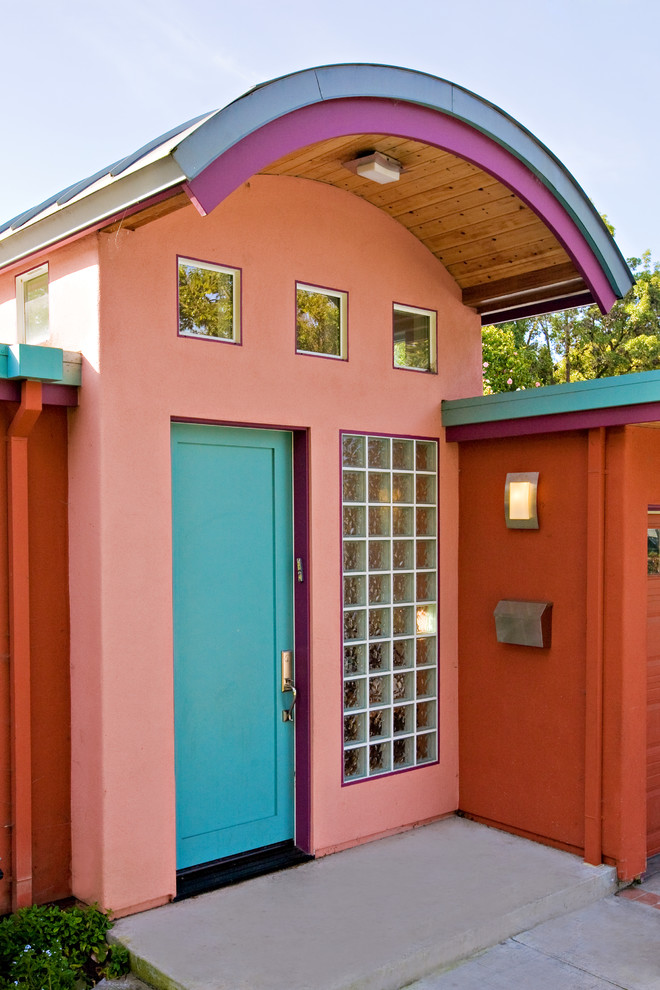 Inspiration pour une porte d'entrée bohème avec un mur rose, sol en béton ciré, une porte simple, une porte bleue et un sol gris.