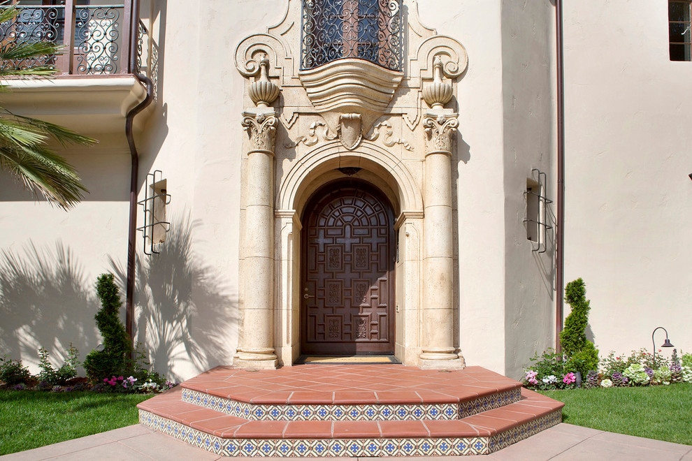 На фото: большая входная дверь в средиземноморском стиле с бежевыми стенами, полом из терракотовой плитки, одностворчатой входной дверью и входной дверью из темного дерева