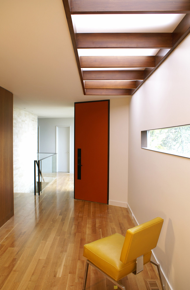 This is an example of a medium sized modern foyer in San Francisco with white walls, light hardwood flooring, a single front door and a red front door.