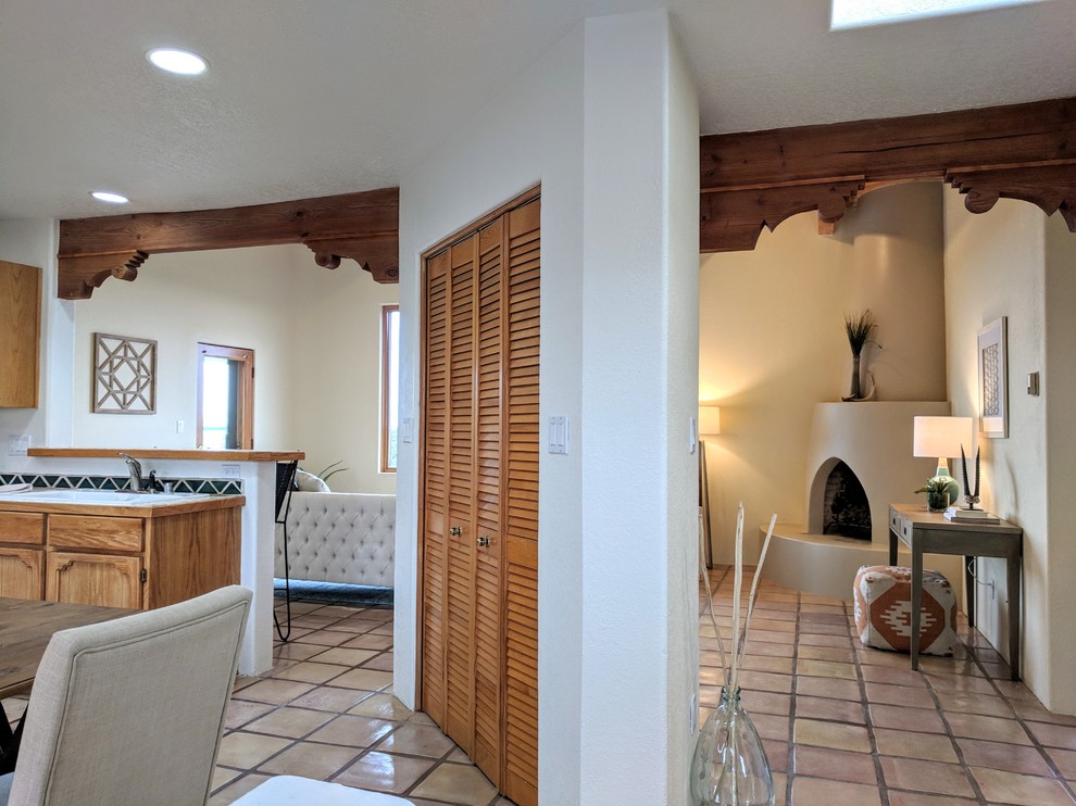 他の地域にある小さなサンタフェスタイルのおしゃれな玄関ロビー (黄色い壁、テラコッタタイルの床、木目調のドア、ベージュの床) の写真