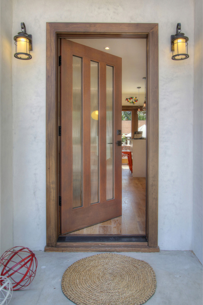 Small eclectic front door in Los Angeles with white walls, light hardwood flooring, a single front door and a dark wood front door.