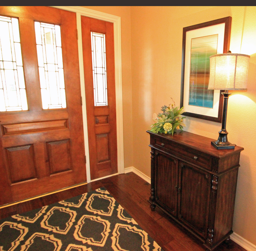 Kleines Klassisches Foyer mit beiger Wandfarbe, dunklem Holzboden, Einzeltür und hellbrauner Holzhaustür in Dallas