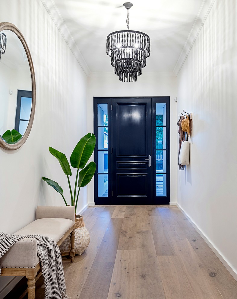 Idee per un ingresso tradizionale con pareti bianche, pavimento in legno massello medio, una porta singola, una porta nera e pavimento marrone