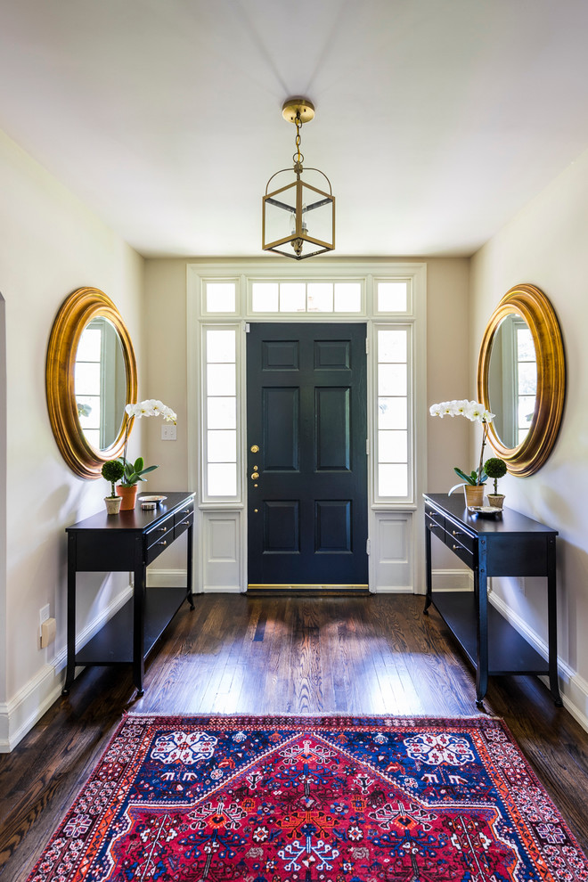 Aménagement d'un grand hall d'entrée classique avec un mur beige, parquet foncé, une porte simple, une porte noire et un sol marron.