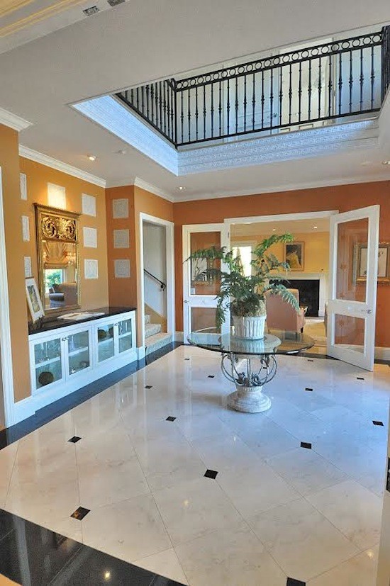 Large elegant porcelain tile and white floor foyer photo in Los Angeles with orange walls