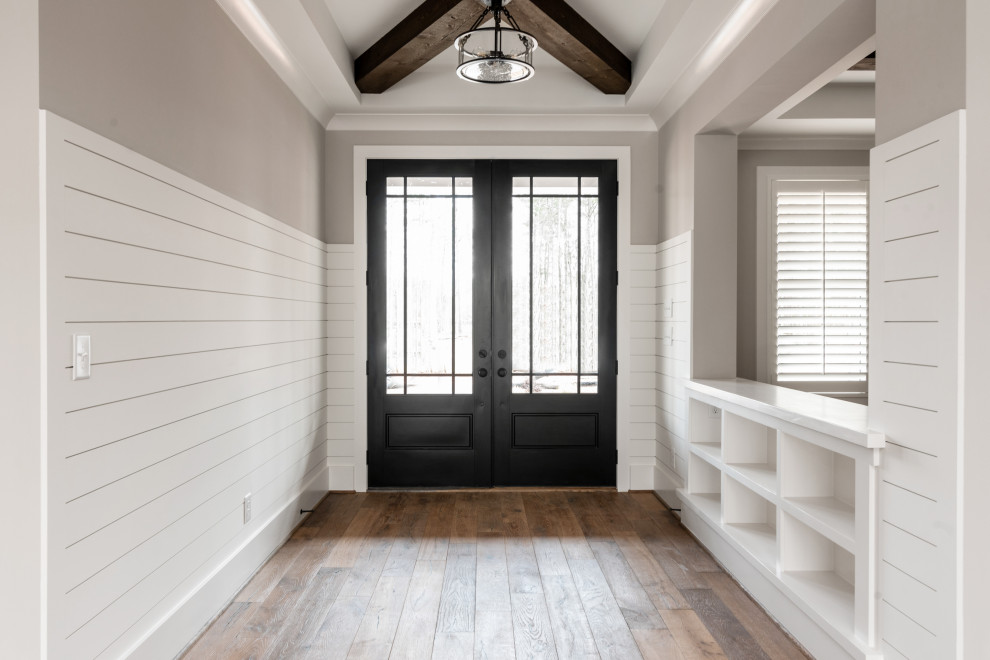 Esempio di un ingresso o corridoio american style con pareti beige, pavimento in legno massello medio, travi a vista e pareti in perlinato