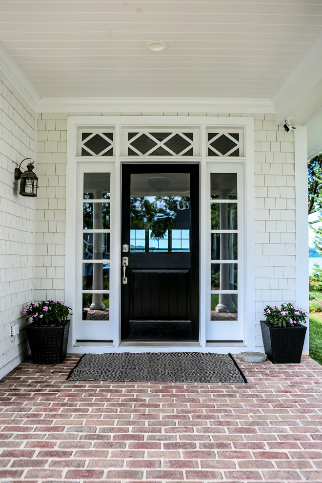 Ejemplo de puerta principal clásica grande con paredes blancas, suelo de ladrillo, puerta simple, puerta negra y suelo rojo