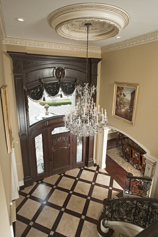 На фото: огромное фойе в классическом стиле с бежевыми стенами, мраморным полом, одностворчатой входной дверью и входной дверью из темного дерева с