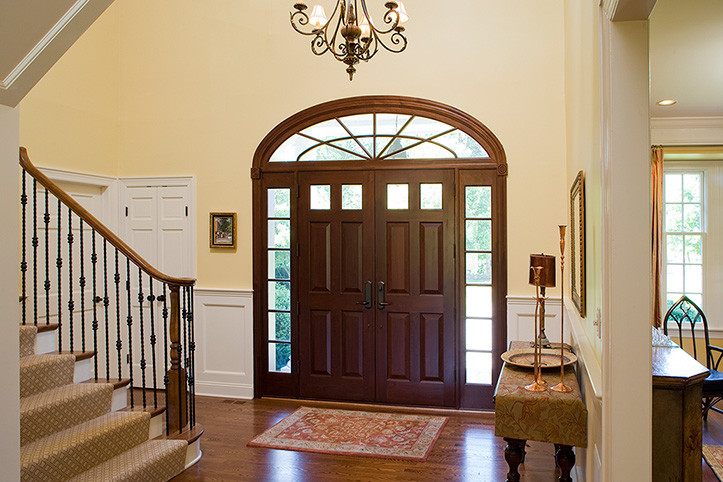 Klassisches Foyer mit gelber Wandfarbe, braunem Holzboden, Doppeltür und hellbrauner Holzhaustür in New York