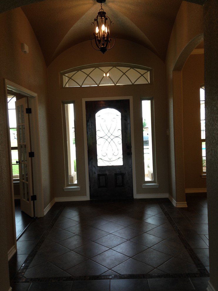Kleines Klassisches Foyer mit brauner Wandfarbe, Porzellan-Bodenfliesen, Einzeltür und dunkler Holzhaustür in Austin