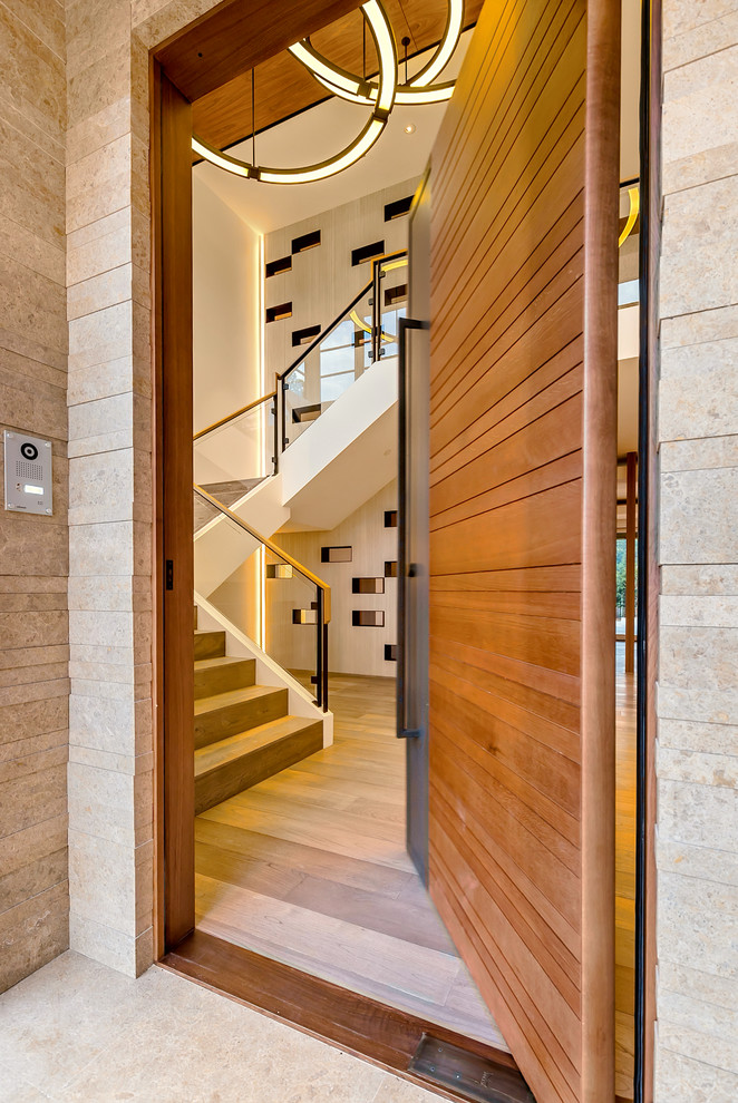 Idee per un'ampia porta d'ingresso moderna con pareti bianche, pavimento in legno massello medio, una porta a pivot e una porta in legno bruno