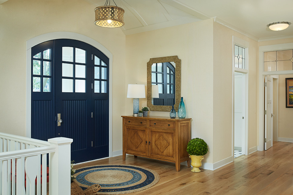 Idées déco pour un grand hall d'entrée classique avec un mur beige, un sol en bois brun, une porte simple, une porte bleue et un sol marron.