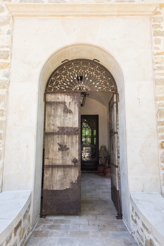 Exemple d'une entrée méditerranéenne avec un sol en brique, une porte double et une porte en bois clair.