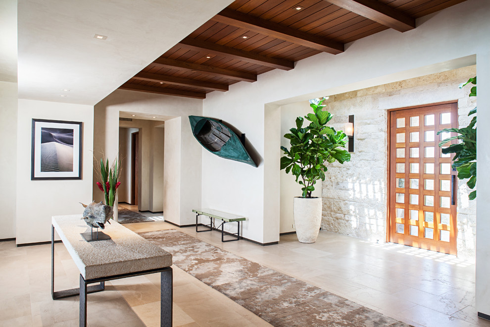 Aménagement d'un hall d'entrée contemporain avec un mur blanc, un sol en travertin, une porte pivot et une porte en bois brun.