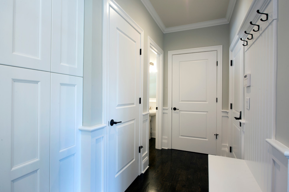 Стильный дизайн: тамбур в классическом стиле с белыми стенами, темным паркетным полом, поворотной входной дверью и белой входной дверью - последний тренд