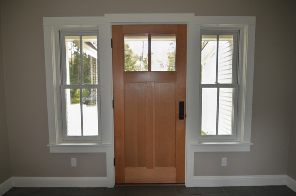 Aménagement d'une grande porte d'entrée classique avec un mur beige, sol en béton ciré, une porte simple, une porte en bois clair et un sol gris.