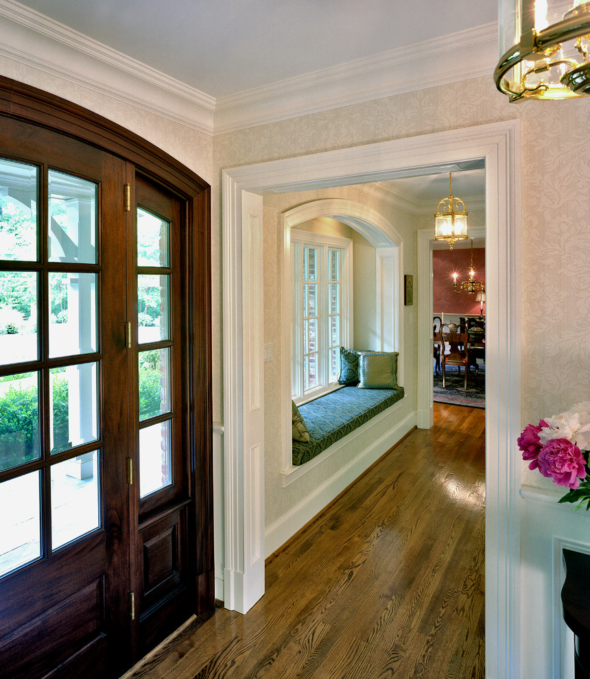 Foto de distribuidor clásico con paredes beige, suelo de madera en tonos medios, puerta simple y puerta de madera oscura