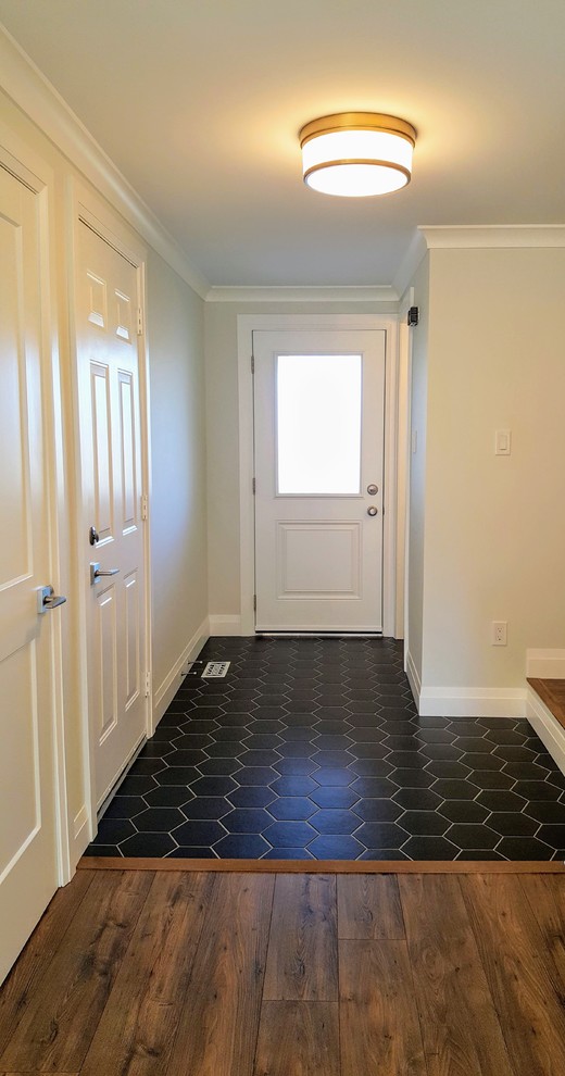 Cette photo montre une grande entrée éclectique avec un couloir, un mur blanc, une porte simple et un sol noir.