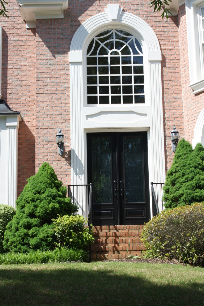 На фото: фойе в классическом стиле с паркетным полом среднего тона, двустворчатой входной дверью и черной входной дверью