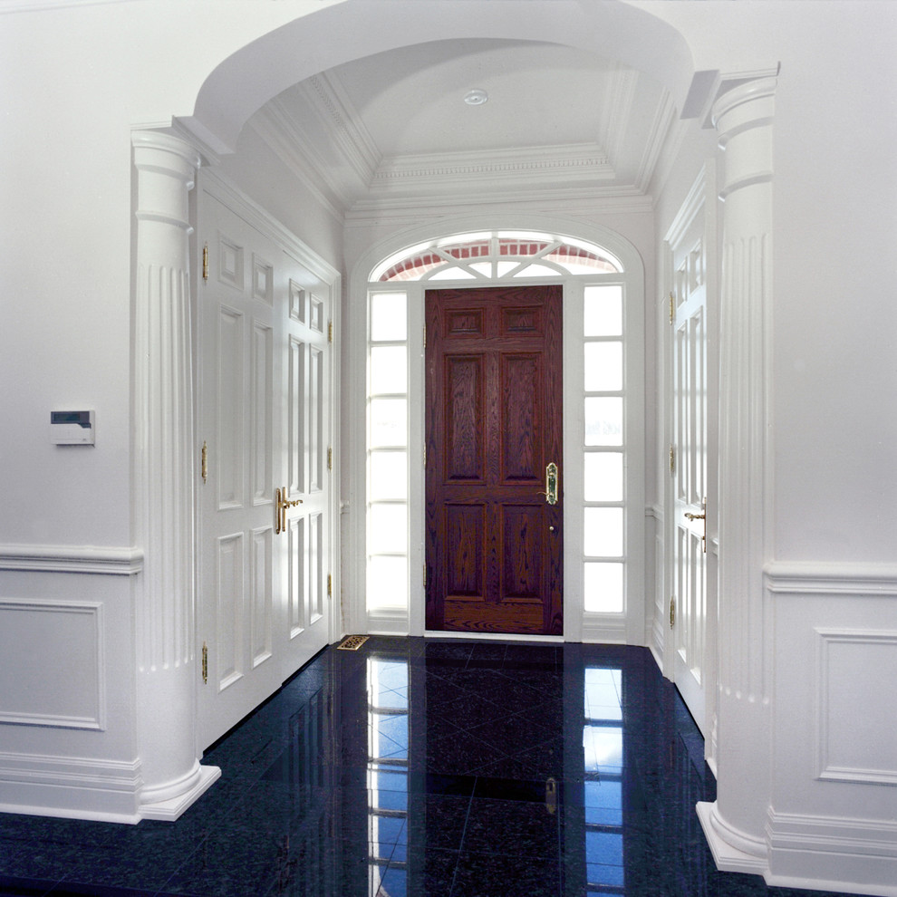 На фото: входная дверь среднего размера в классическом стиле с белыми стенами, гранитным полом, одностворчатой входной дверью, входной дверью из темного дерева и черным полом с