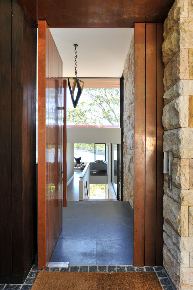 Aménagement d'une grande porte d'entrée contemporaine avec un sol en ardoise, une porte pivot et une porte métallisée.