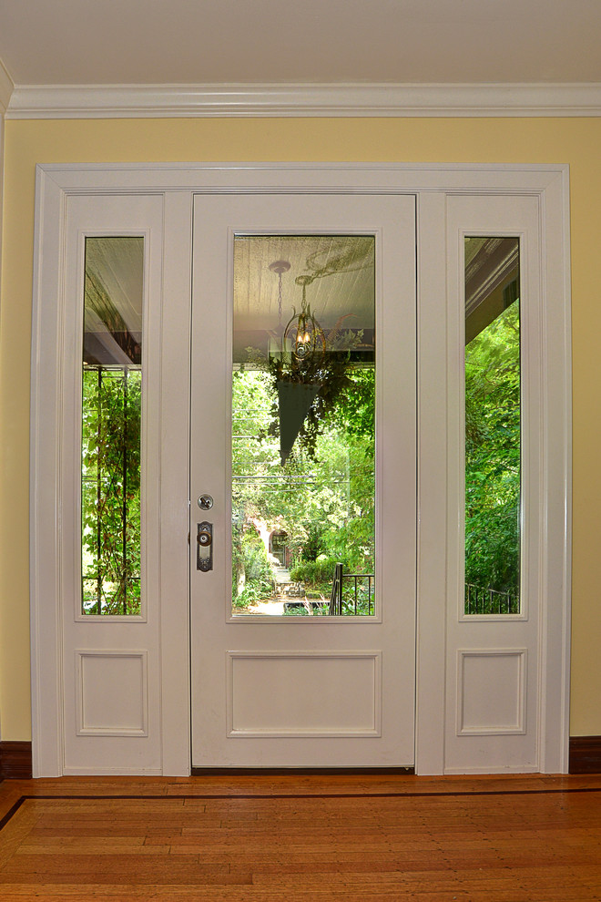 Example of a large trendy light wood floor entryway design in Other with beige walls and a white front door