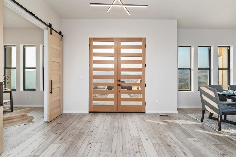 Foto de distribuidor moderno de tamaño medio con puerta doble, puerta de madera clara, paredes blancas, suelo laminado y suelo gris