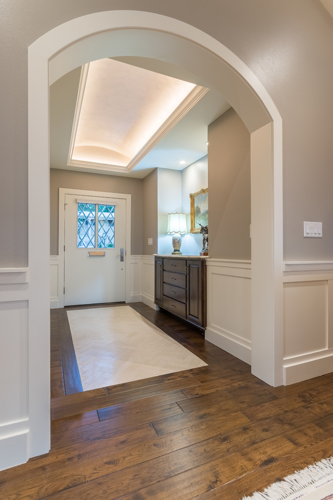 Ejemplo de vestíbulo tradicional de tamaño medio con paredes beige, suelo de madera en tonos medios, puerta simple y puerta blanca