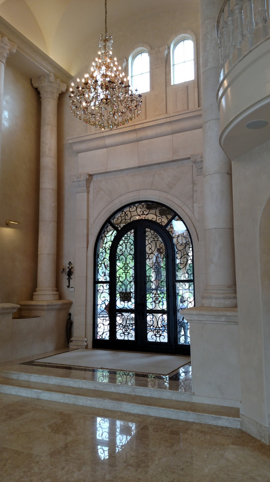 Exemple d'un très grand hall d'entrée chic avec un mur beige, un sol en marbre, une porte double, une porte noire, un sol beige et un plafond voûté.