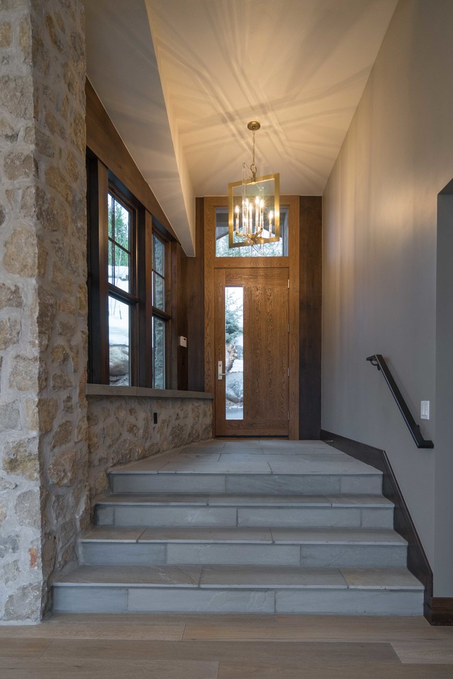Idées déco pour un hall d'entrée moderne de taille moyenne avec un mur gris, un sol en ardoise, une porte simple, une porte en bois brun et un sol gris.