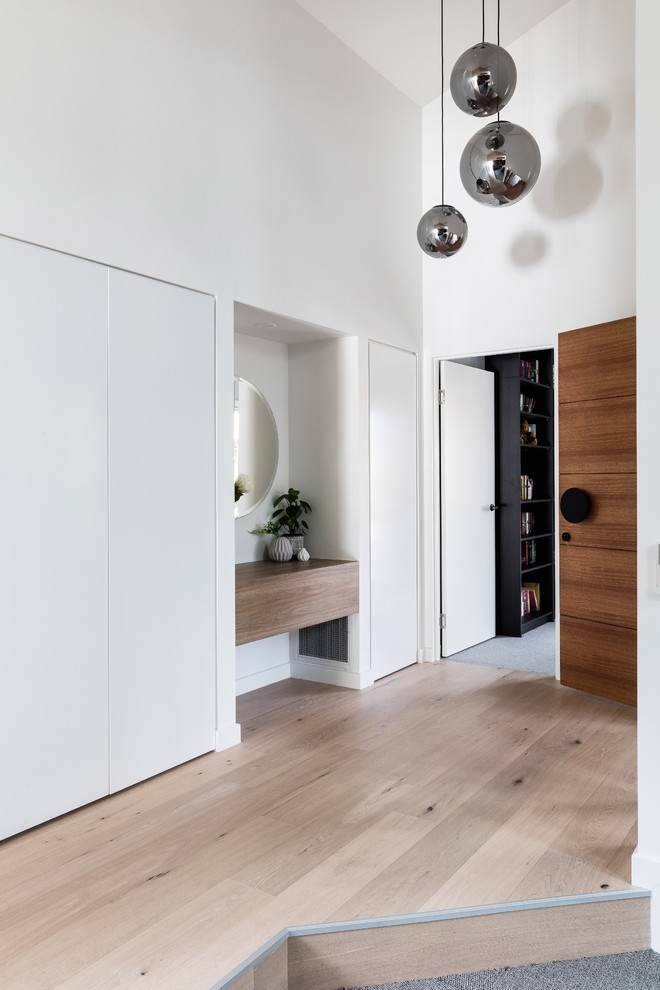 Esempio di un ingresso moderno di medie dimensioni con pareti bianche, pavimento in laminato, una porta singola, una porta in legno bruno e pavimento marrone