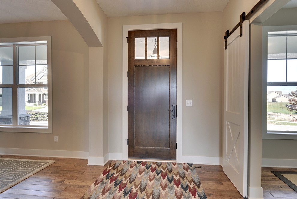 Large transitional medium tone wood floor entryway photo in Minneapolis with beige walls and a dark wood front door