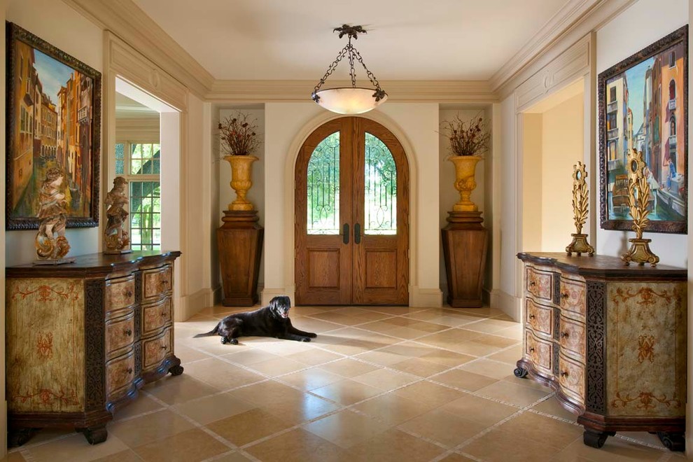 ダラスにあるラグジュアリーな巨大な地中海スタイルのおしゃれな玄関ロビー (トラバーチンの床、木目調のドア) の写真