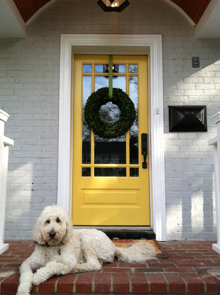 Cette image montre une porte d'entrée avec une porte simple et une porte jaune.