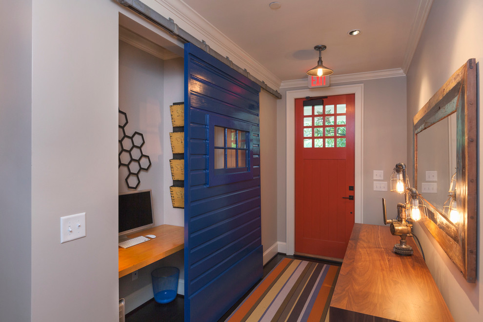 Esempio di un corridoio design con pareti beige, una porta singola, una porta rossa e pavimento multicolore