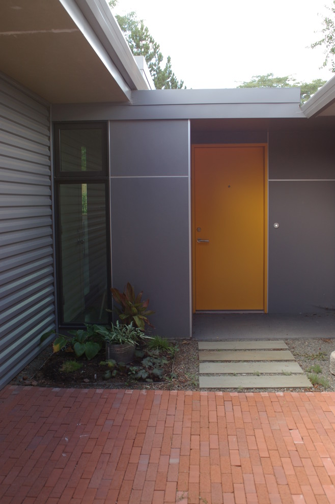 Immagine di un ingresso o corridoio moderno con pareti grigie, una porta singola e una porta arancione