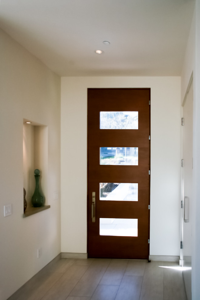 Foto de distribuidor contemporáneo de tamaño medio con paredes blancas, suelo de baldosas de porcelana, puerta simple y puerta de madera oscura