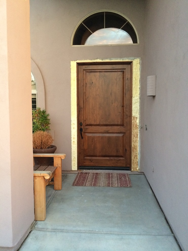 На фото: большая входная дверь в средиземноморском стиле с фиолетовыми стенами, бетонным полом, одностворчатой входной дверью и входной дверью из дерева среднего тона с