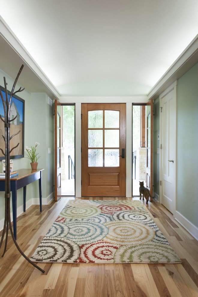 Cette image montre une entrée design avec un mur vert, une porte simple et une porte en bois brun.