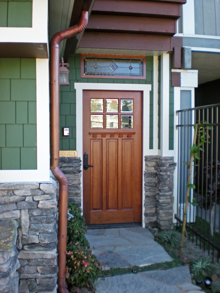 Cette image montre une porte d'entrée craftsman de taille moyenne avec un mur vert, un sol en ardoise, une porte simple et une porte en bois brun.