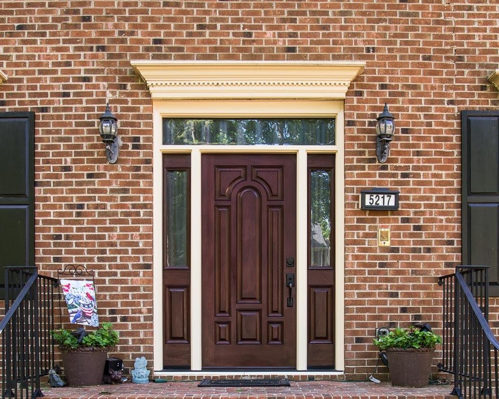 Imagen de puerta principal tradicional de tamaño medio con paredes blancas, suelo de ladrillo, puerta simple y puerta marrón