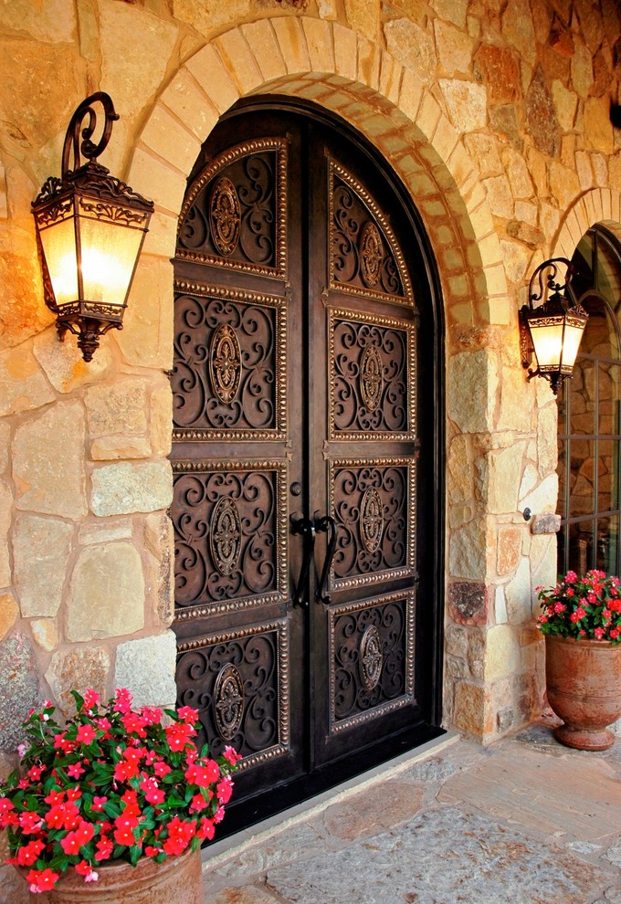 Medelhavsstil inredning av en ingång och ytterdörr, med gula väggar, kalkstensgolv, en dubbeldörr och en brun dörr