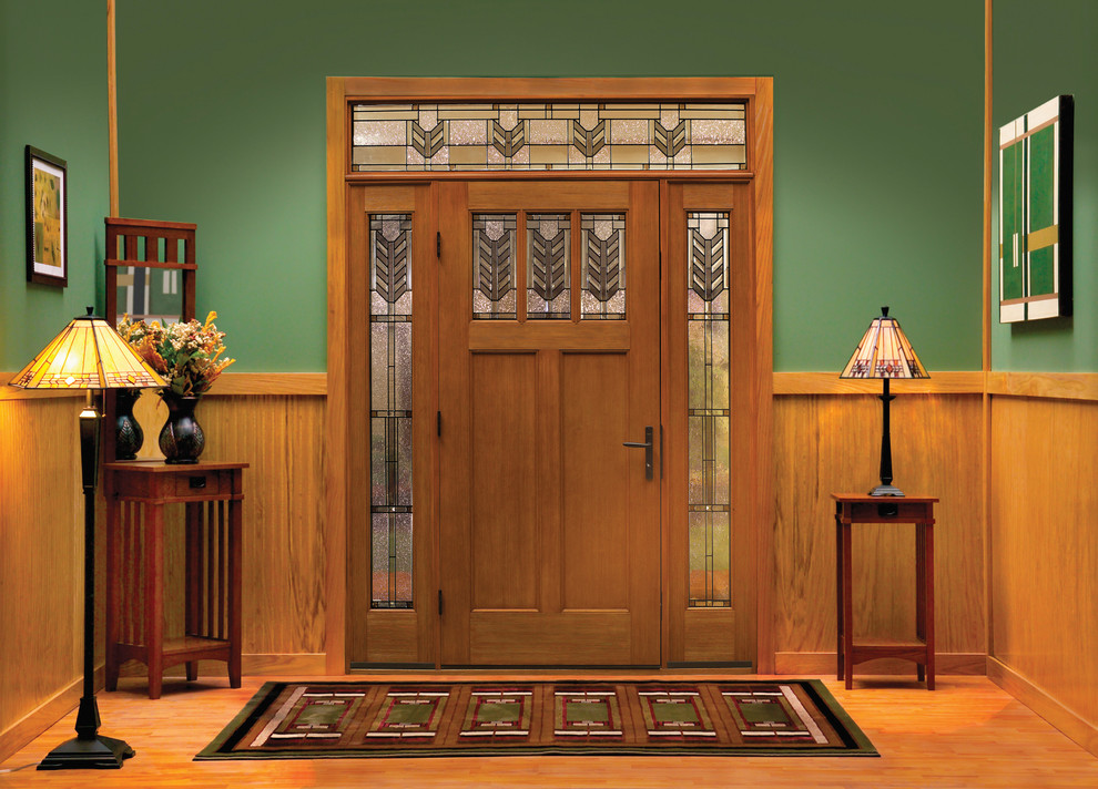 Cette image montre une porte d'entrée craftsman de taille moyenne avec un mur vert, parquet clair, une porte simple et une porte en bois brun.