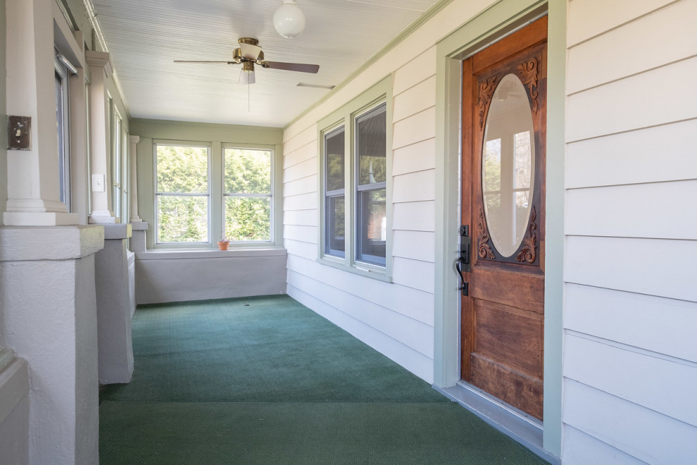Cette photo montre un vestibule craftsman de taille moyenne avec un mur blanc, moquette, une porte simple, une porte en bois brun et un sol vert.