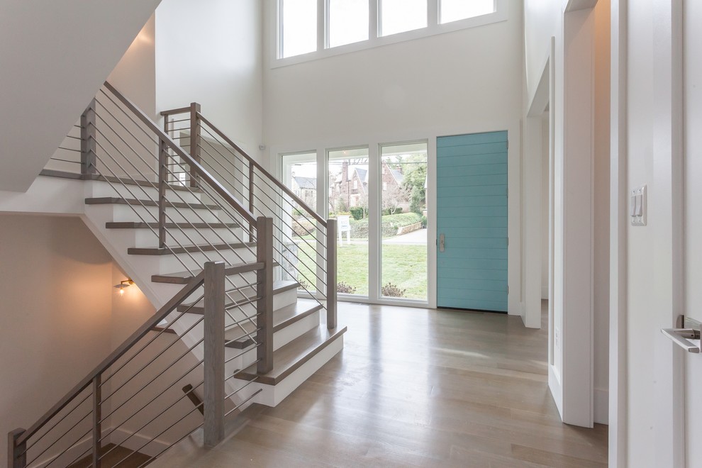 Cette photo montre un hall d'entrée tendance avec un mur blanc, parquet clair, une porte simple, une porte bleue et un sol gris.