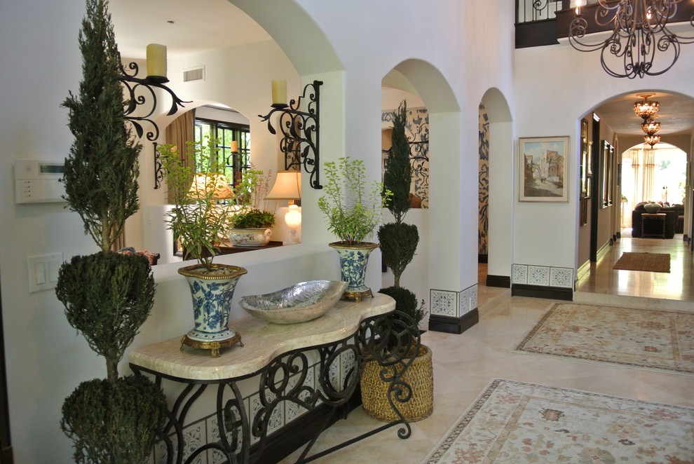 Пример оригинального дизайна: фойе среднего размера в средиземноморском стиле с белыми стенами, полом из травертина, одностворчатой входной дверью, коричневой входной дверью и бежевым полом