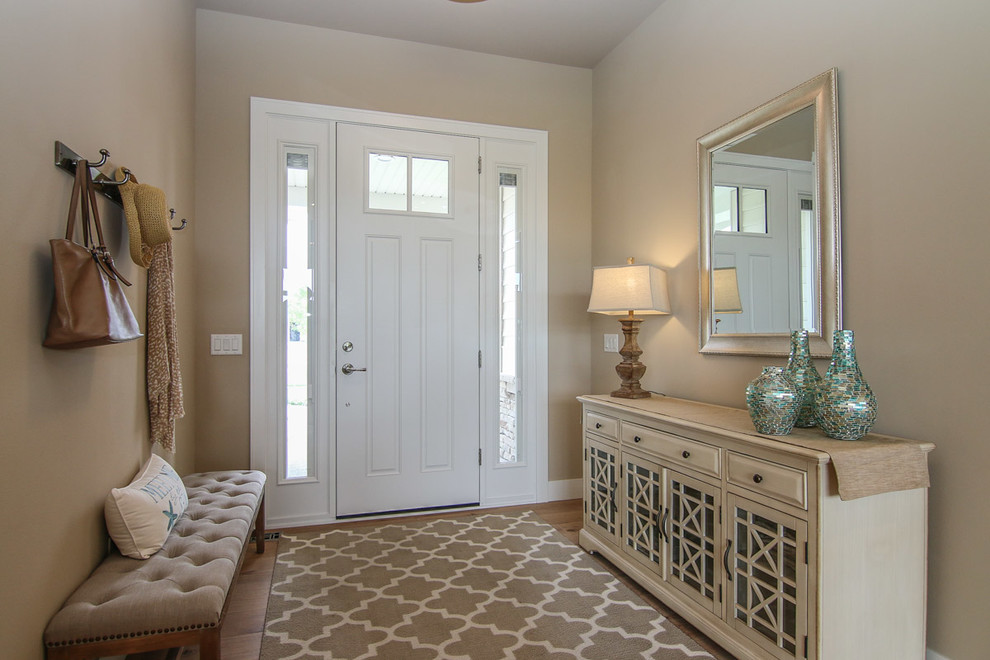 Immagine di una porta d'ingresso stile marinaro di medie dimensioni con pareti beige, pavimento in legno massello medio, una porta singola e una porta bianca
