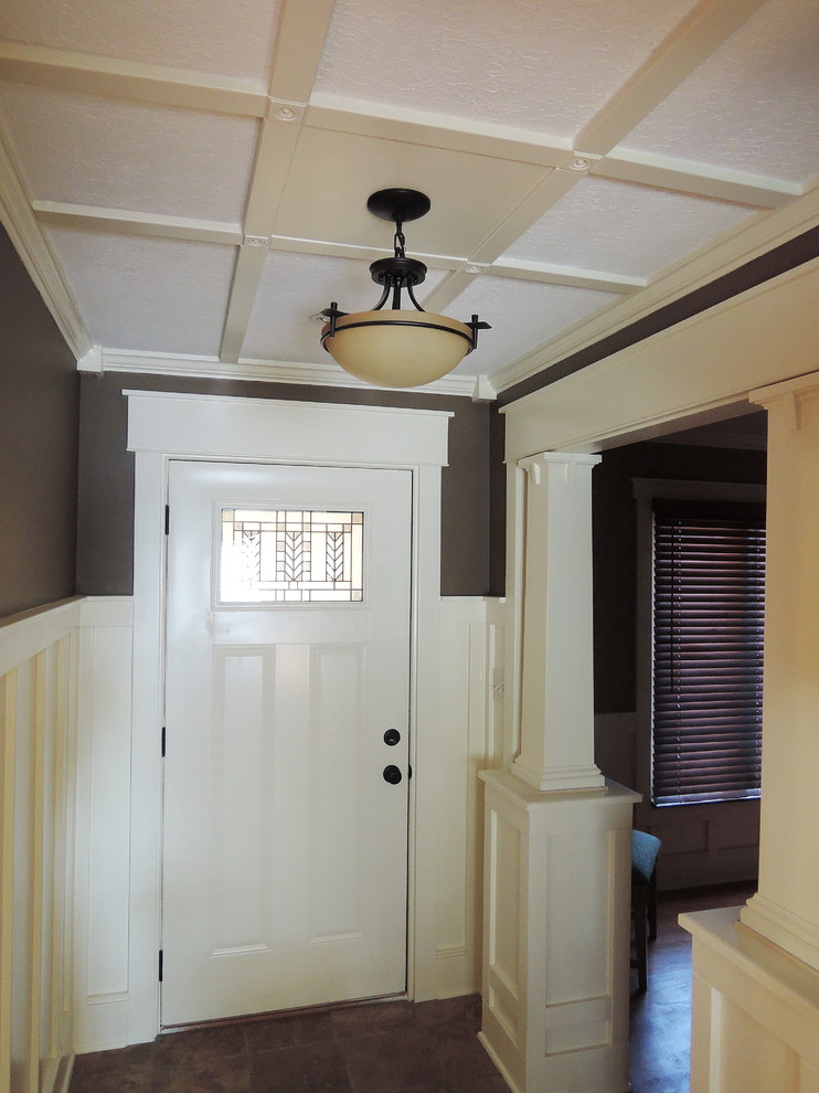 Aménagement d'un petit hall d'entrée craftsman avec un mur marron, un sol en travertin, une porte simple et une porte blanche.